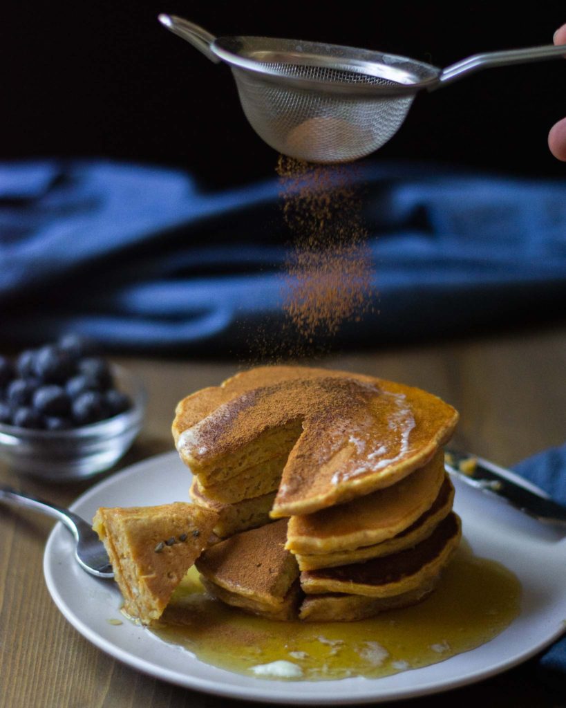 sweet potato pancakes being dusted with ground cinnamon