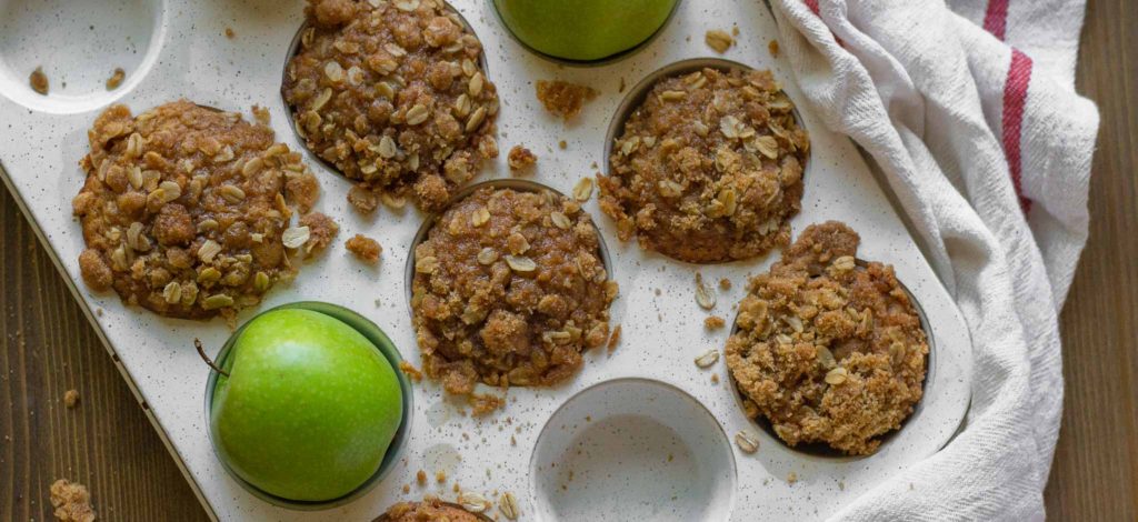 apple cider muffins and a green apple in a muffin tin