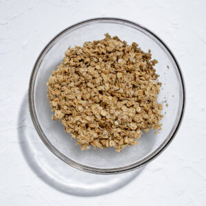 Granola ingredients combined so that oats are evenly covered and ready to be spread on a baking tray.