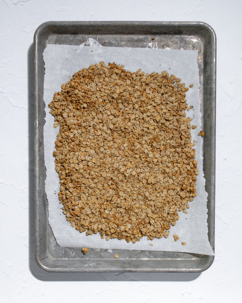 Half-baked granola patted into an even layer before going back into the oven to finish baking.