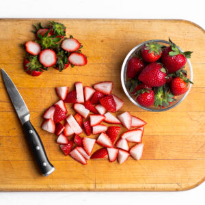 Sweet fresh strawberries that are in the process of being quartered to be roasted for scones.