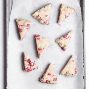 Eight scones are placed on a lined baking sheet so that they aren't touching.