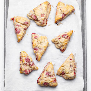 Pink and red strawberry slices show through the scones that have been baked until golden brown and slightly firm to the touch.
