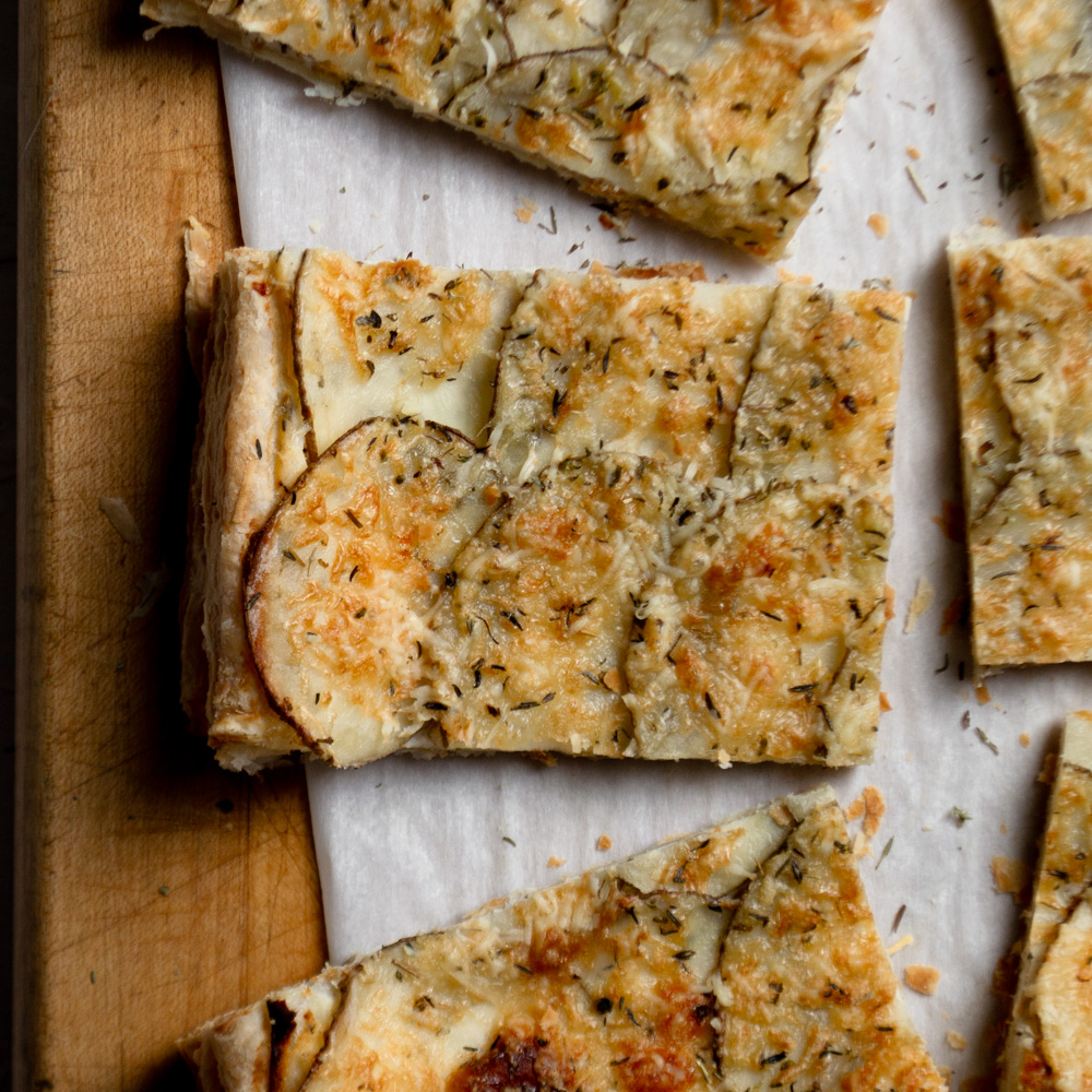 A single slice of cheesy potato breakfast tart with beautifully layered, thin-sliced potatoes, herbs, and crispy parmesan cheese.