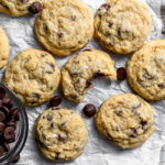 Cooling homemade chocolate chip cookies with a tasty bite taken out of one to reveal a soft and gooey center.