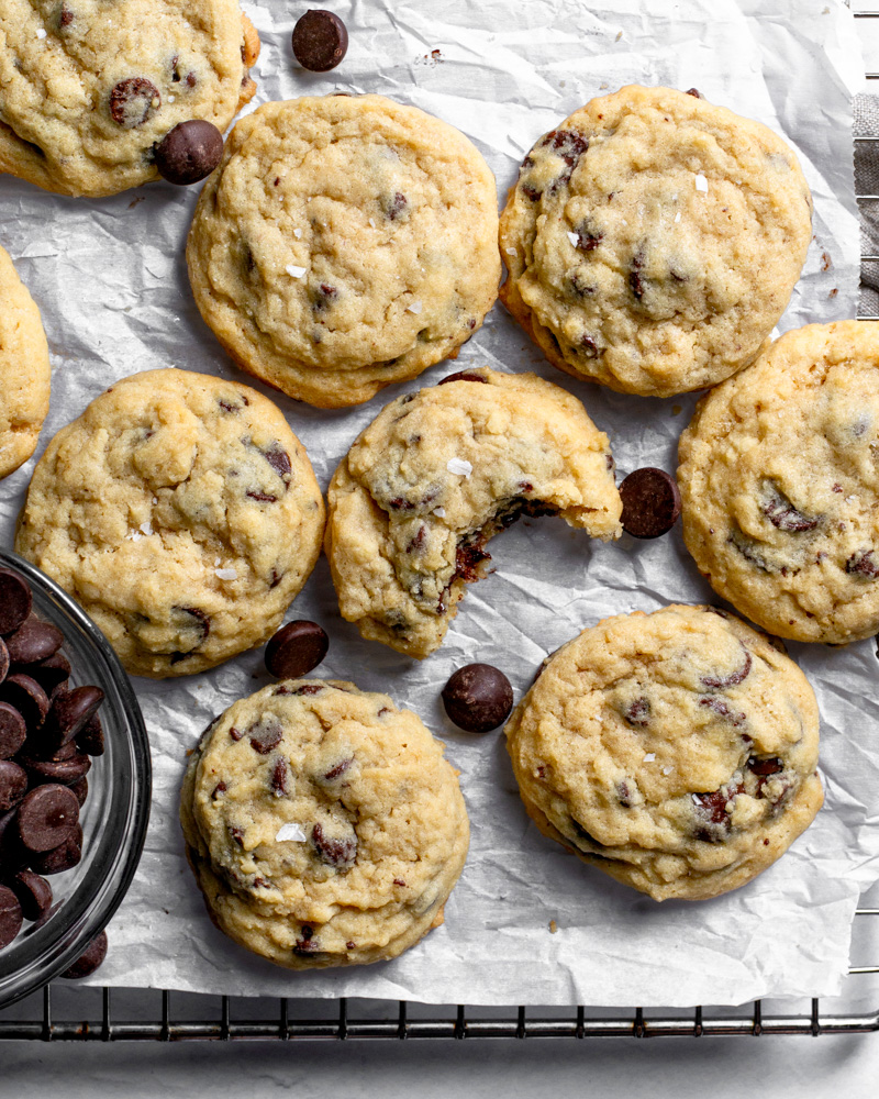 Cooling homemade chocolate chip cookies with a tasty bite taken out of one to reveal a soft and gooey center.