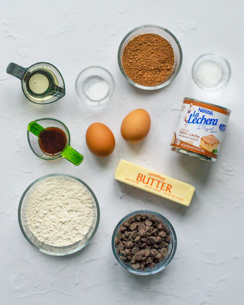 Salted dulce de leche brownie ingredients! Cocoa powder, kosher salt, vegetable oil, vanilla extract, large eggs, canned dulce de leche, unsalted butter, all-purpose flour, semisweet chocolate chips, and granulated sugar.