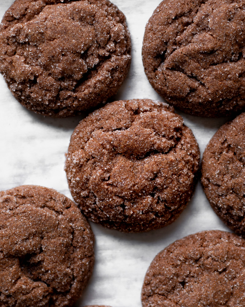 Perfectly round and slightly crinkled chocolate cookies, shimmering with a coat of granulated sugar.