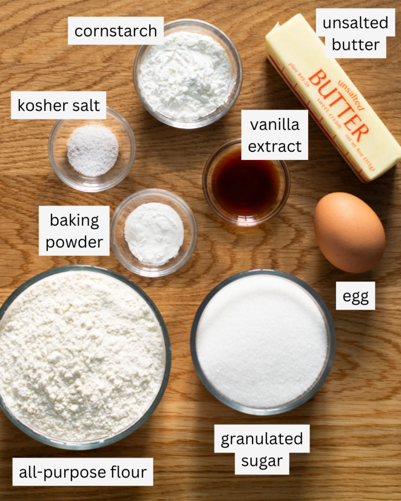 Ingredients to be used in a recipe for drop style no chill sugar cookies: unsalted butter, a large egg, cornstarch, all-purpose flour, vanilla extract, baking powder, kosher salt, and granulated sugar.