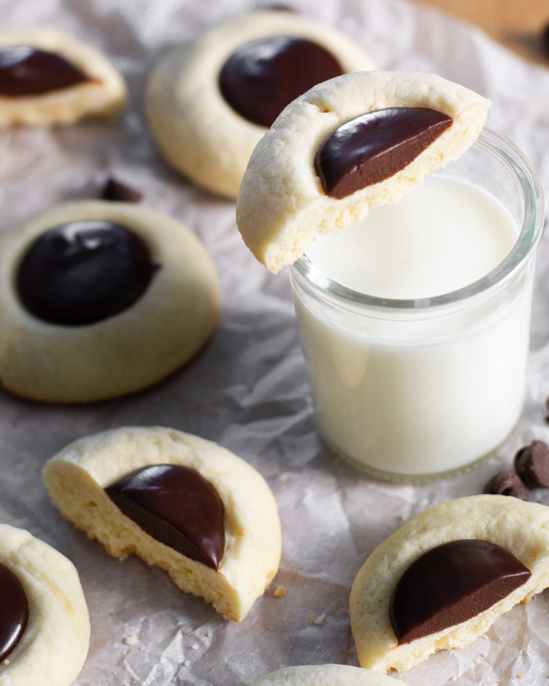 Perfectly portioned chocolate ganache vanilla thumbprint cookies with a silky-smooth semi-sweet chocolate filling and perfectly tender cookies, ready to be dipped in a glass of cold milk.