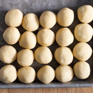 Dough for vanilla thumbprint cookies, rolled into a smooth ball between palms.